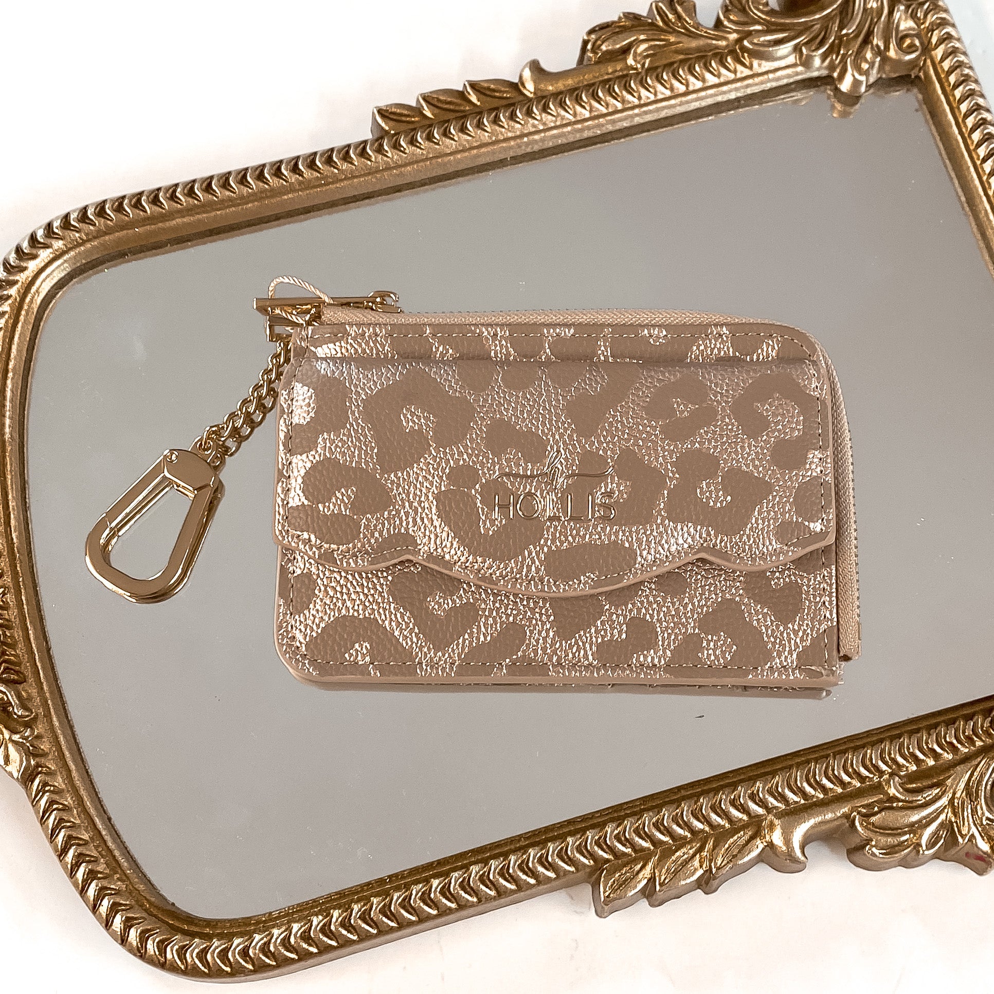 Hollis brand card holder wallet in Leopard. Wallet also has a gold chain connected to it. Pictured on a mirror with a gold frame.