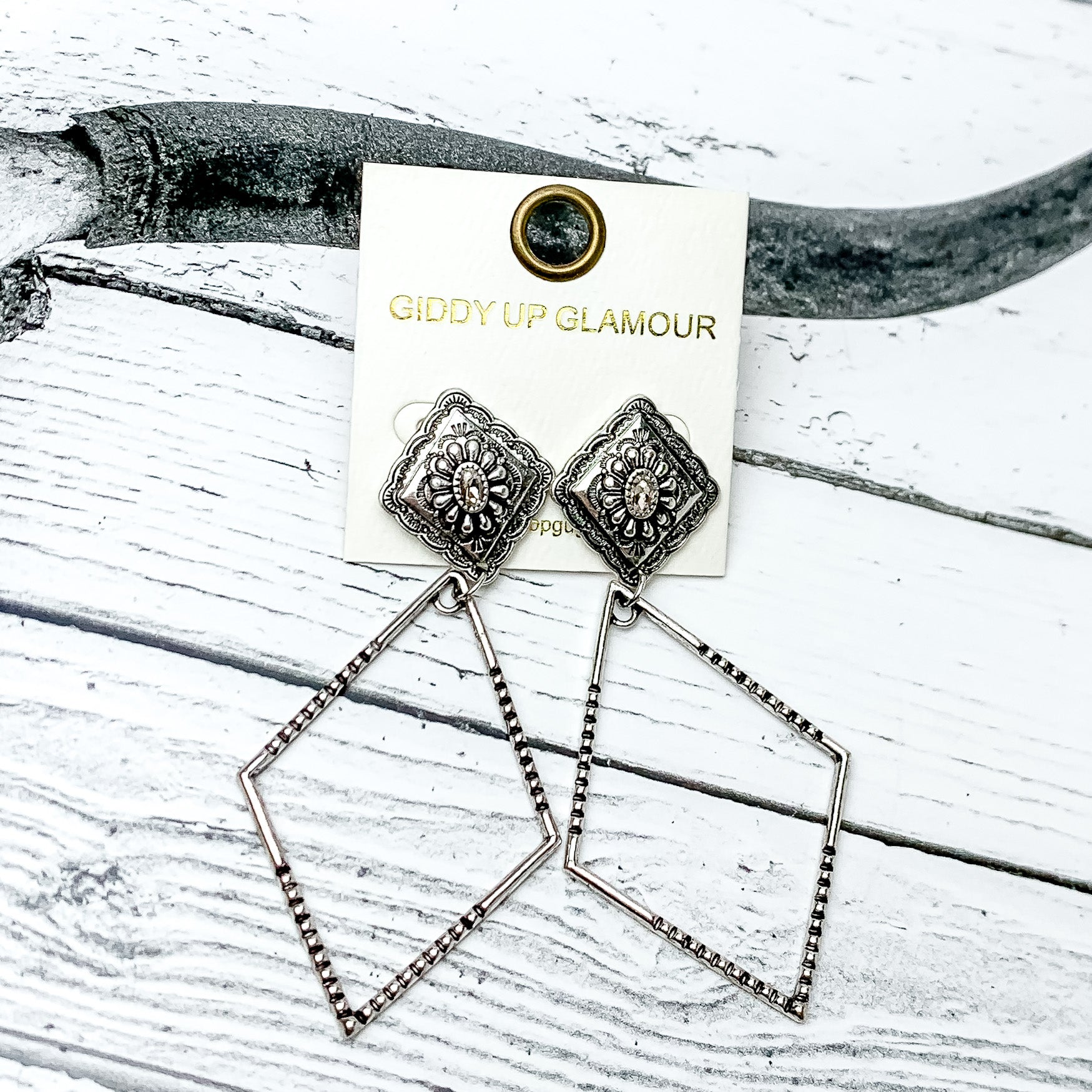 Point of Pretty Diamond Concho Post Earrings with Clear Crystals and Diamond Drop in Silver Tone. Pictured on a western background with a wood texture.