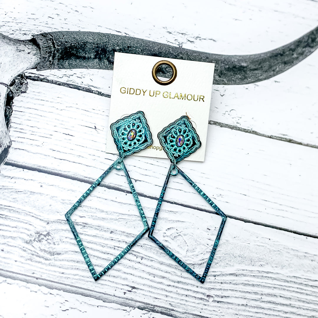 Point of Pretty Diamond Concho Post Earrings with Clear Crystals and Diamond Drop in Patina Tone. Pictured on a western background with wood and a longhorn.