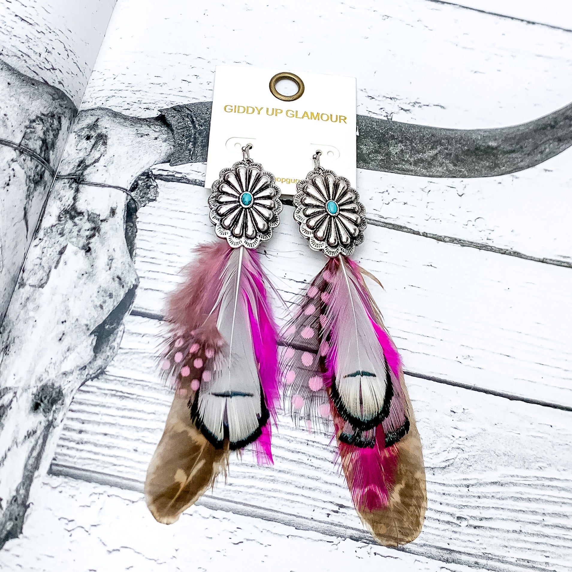 Desert Doll Silver Tone Feather Earrings in Hot Pink. Pictured on an open western book.