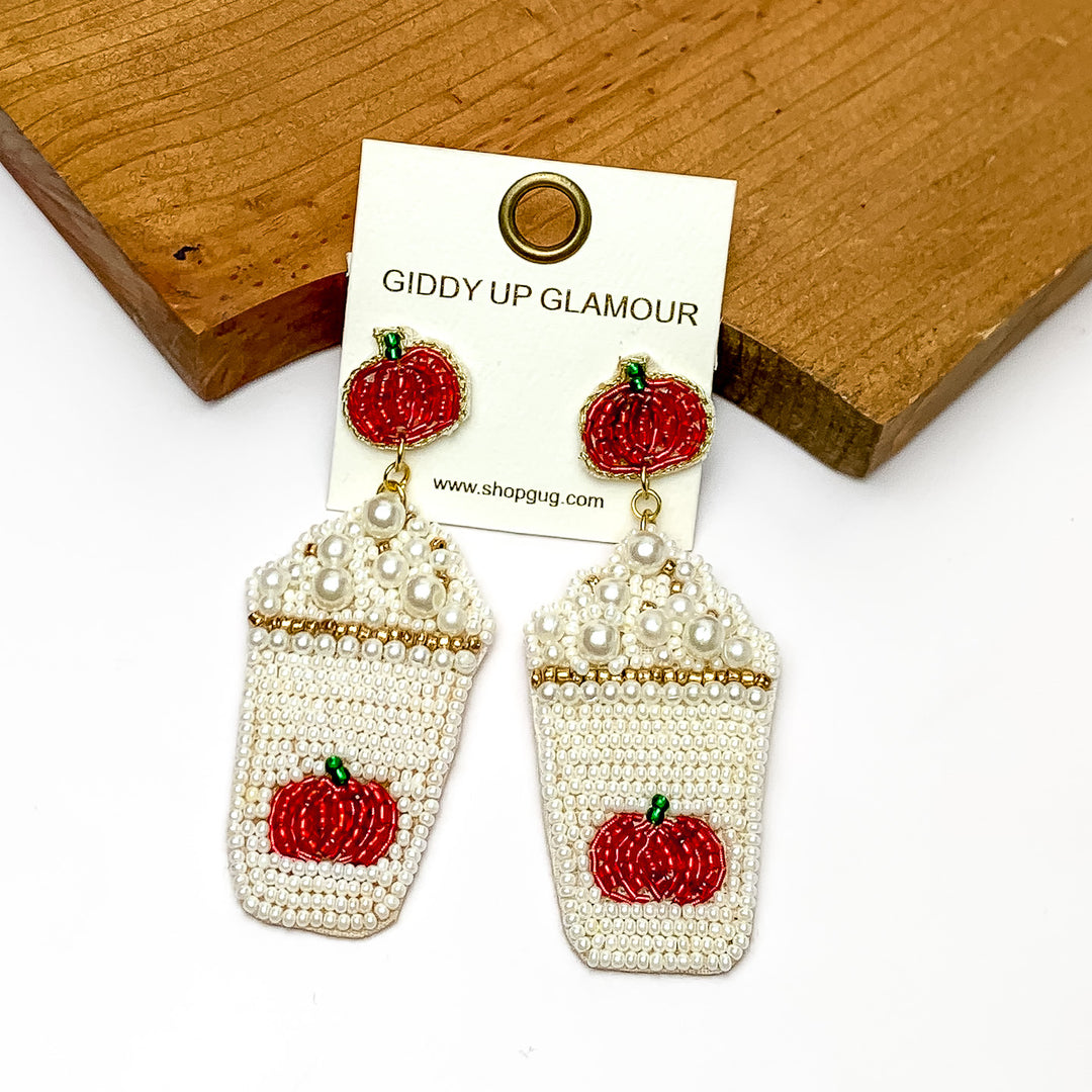 Pumpkin Spice Coffee With The Whip Beaded Earrings. Pictured on a white background with the earrings laying against a piece of wood.