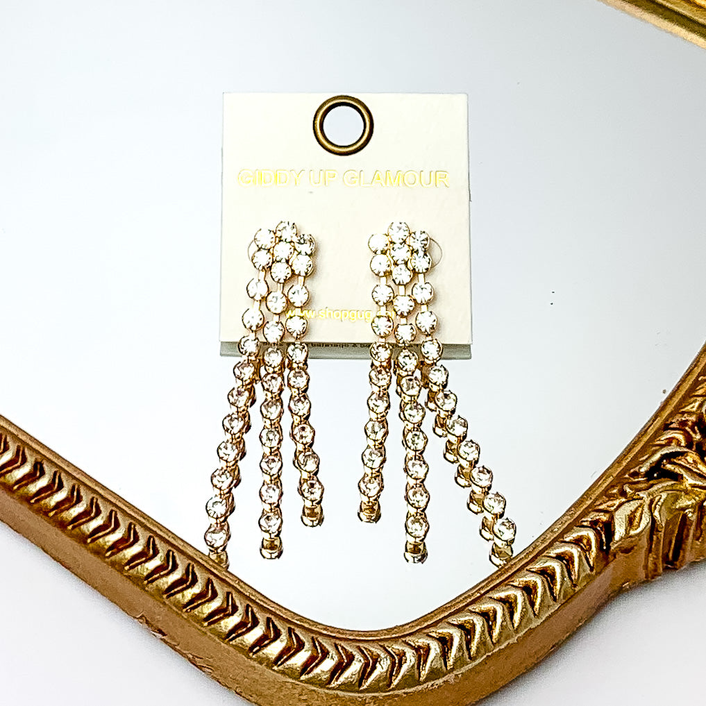 Dazzle Dream Gold Tone Earrings With Clear Crystals. Pictured on a mirror with a gold trim.