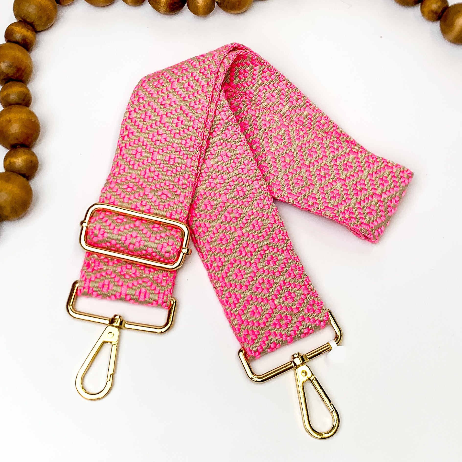 Beaige canvas purse strap with hot pink diamond design. This purse strap includes gold accents. This purse strap is pictured on a white background with brown beads at the top.