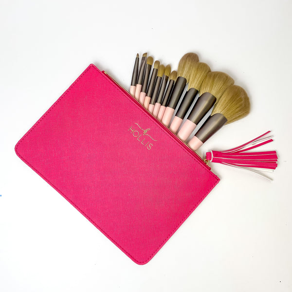 Pictured on a white background is a hot pink bag with an open zipper wiht makeup brushes sticking out. This bag also has a hot pink tassel on the zipper.  