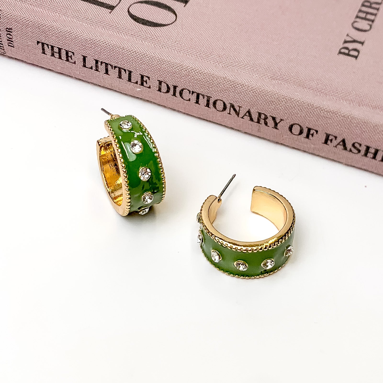 Surrounded By Starlight Small Hoop Earrings in Olive Green. Pictured on a white background with a book above the earrings.