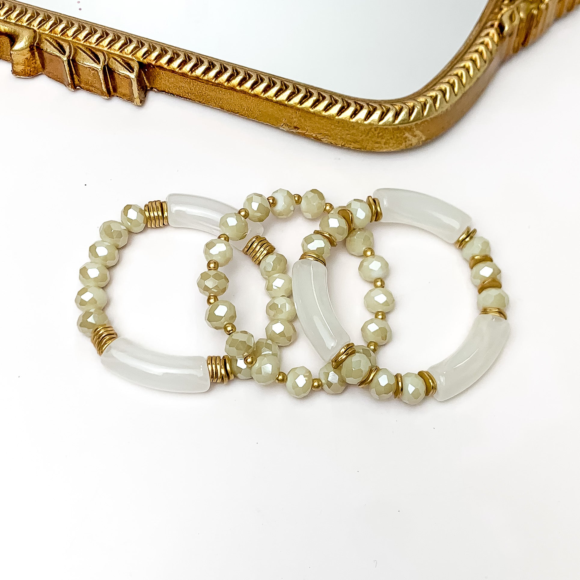 Set of Three | Sunny Bliss Crystal Beaded Bracelet Set in Ivory. Pictured on a white background with a gold trimmed mirror above the bracelets.