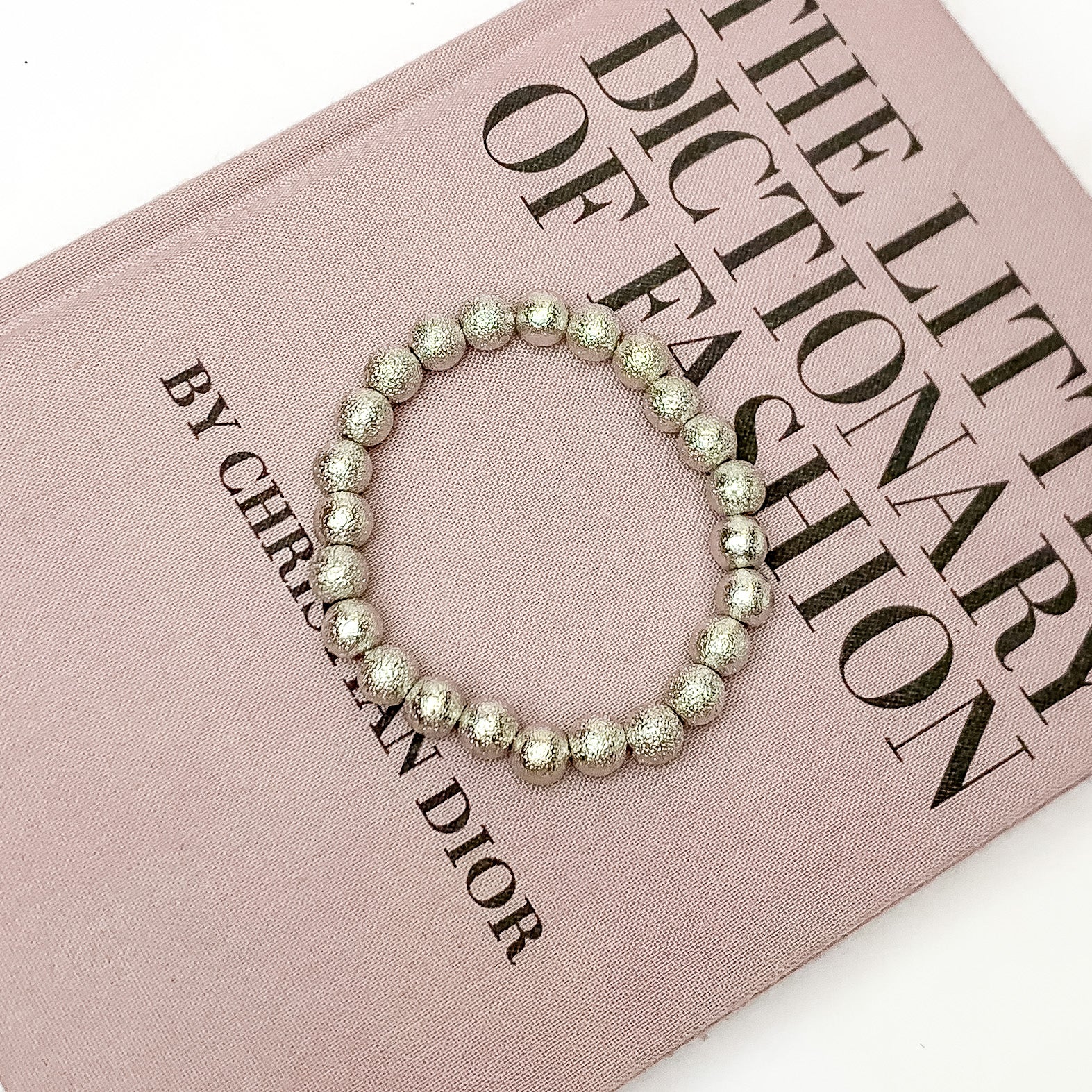 Silver Tone Basic Beaded Bracelet. Pictured laying on top of a closed book. The book is on a white background.