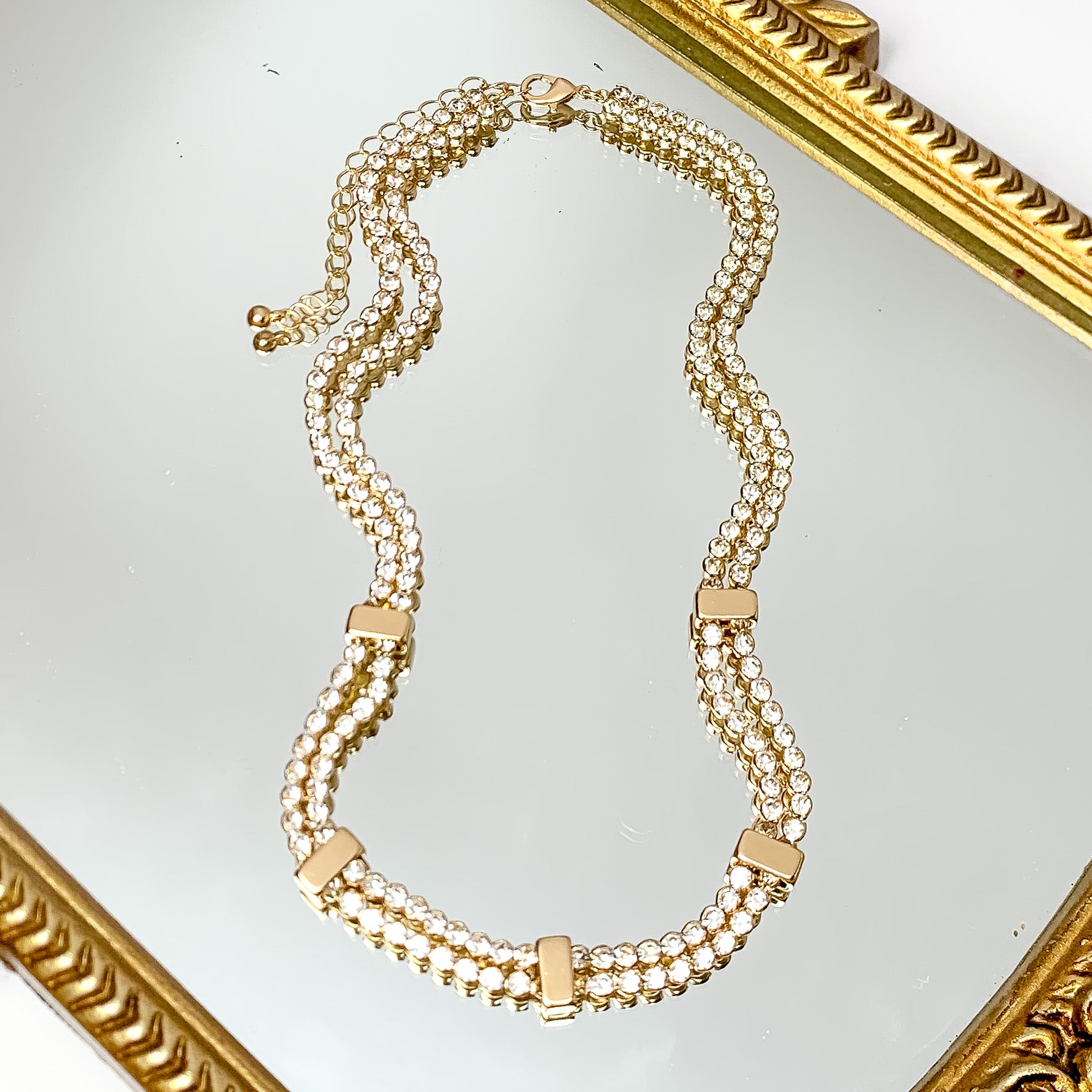 Glam Girl Gold Tone Necklace Outlined in Clear Crystals. Pictured on a white background with disco balls as an accessory on the left side.