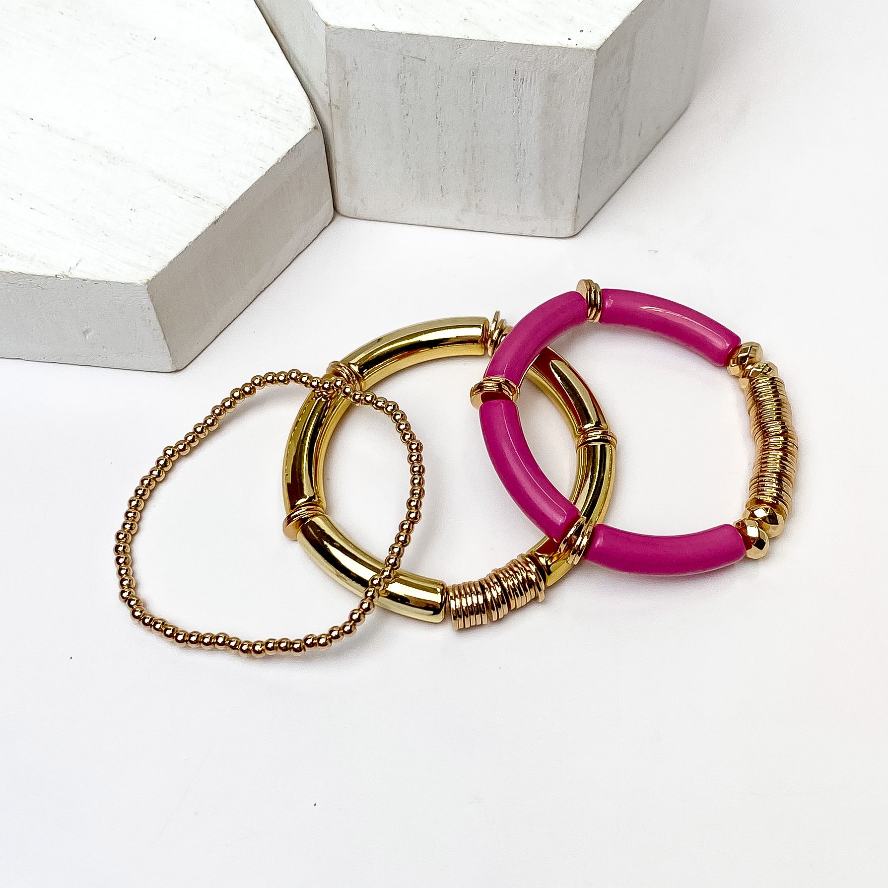 Set of Three | Bahama Nights Gold Tone Tube Bracelet Set in Purple. Pictured on a white background with white platforms above the bracelets.