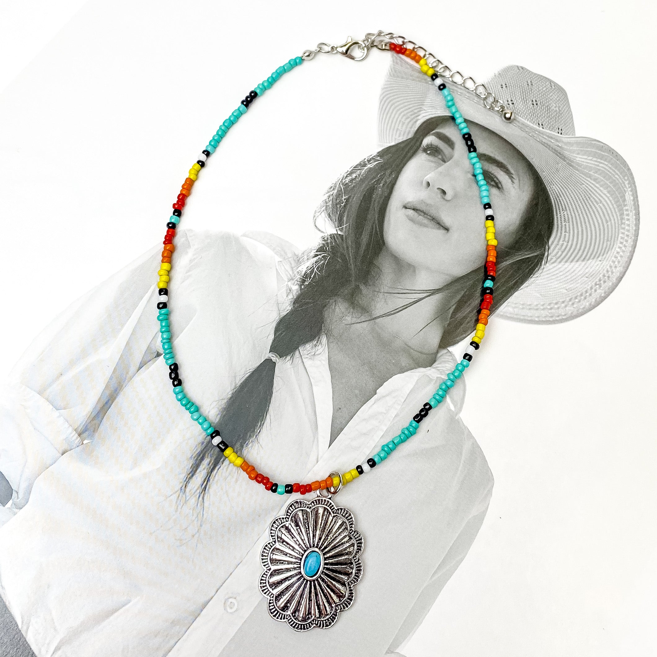 Multicolored Beaded Necklace With Silver Tone Designed Pendant. Pictured on a white and black background. 