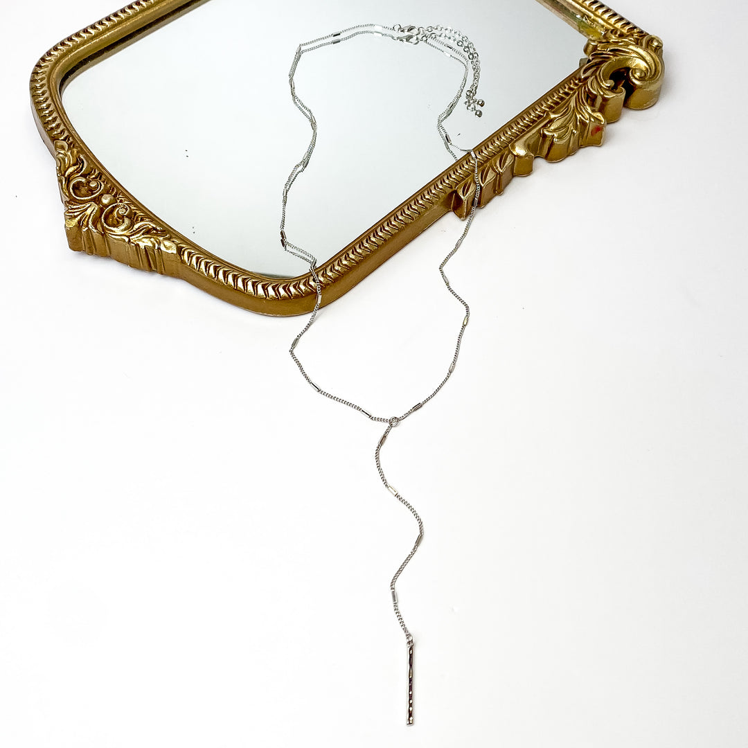 Silver Tone Y Necklace With Hammered Rectangle Charms. Pictured on a white background with the necklace laying on a mirror.