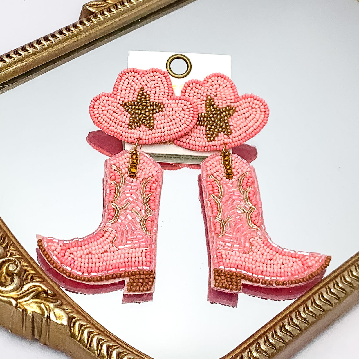 Beaded Cowboy Hat and Boot Earrings with Gold Star in Pink. Pictured on a mirror with a gold trim.