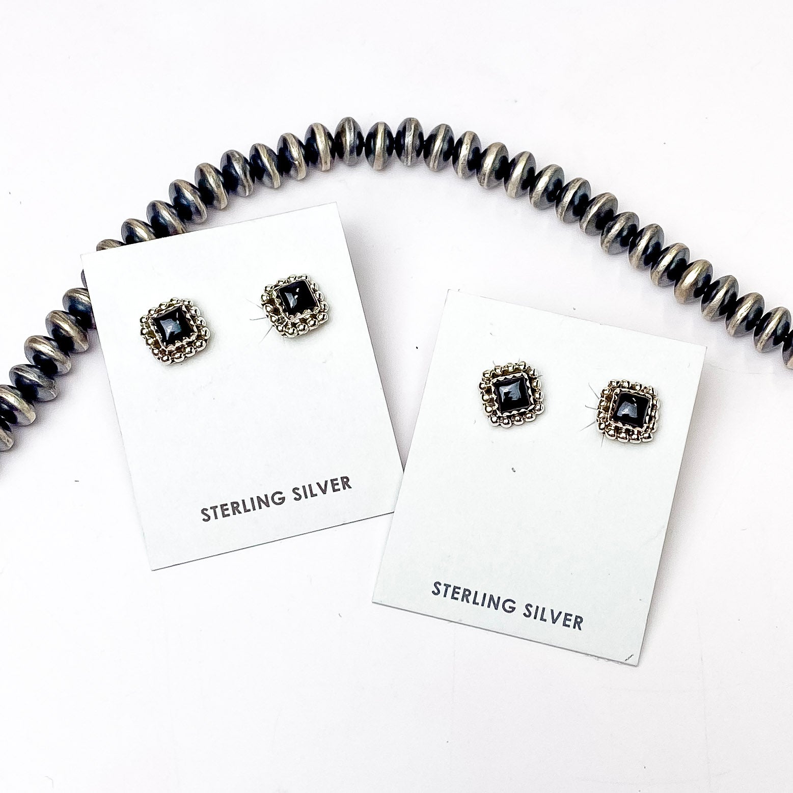 In the picture are sterling silver square shaped stud earrings with black onyx stones with a white background