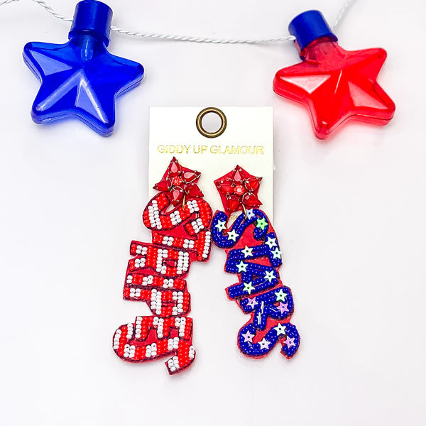 Star shaped earrings with red crystals. One earring has the word "STRIPES" and has red and white beads in a stripe pattern. The other earrings has the word "STARS" in blue beads with white sequin stars. These earrings are pictured on a white background. 
