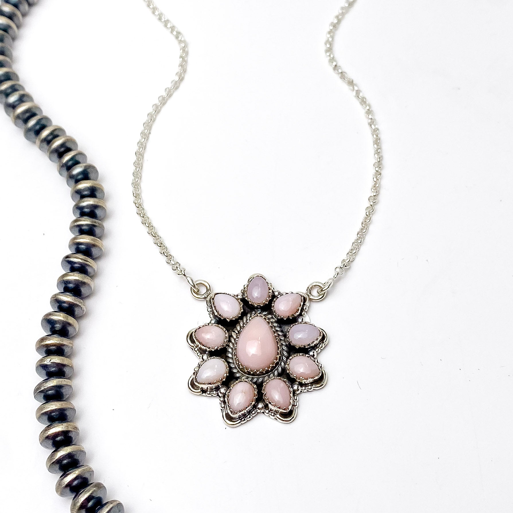 In the picture is a pink opal flower pendant with a white background 