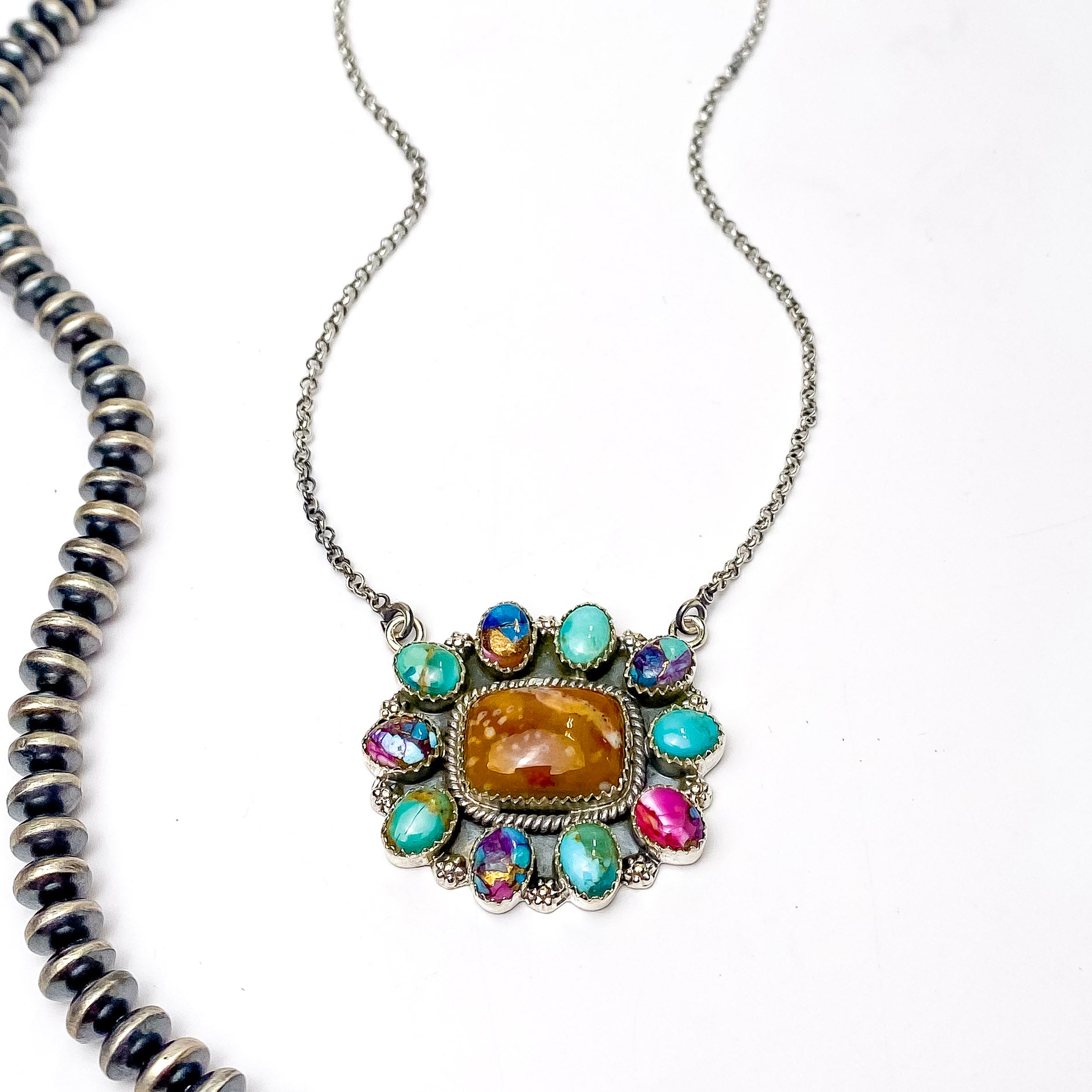 In the picture is a sterling silver flower cluster that is very colorful multi stone necklace with a white background 