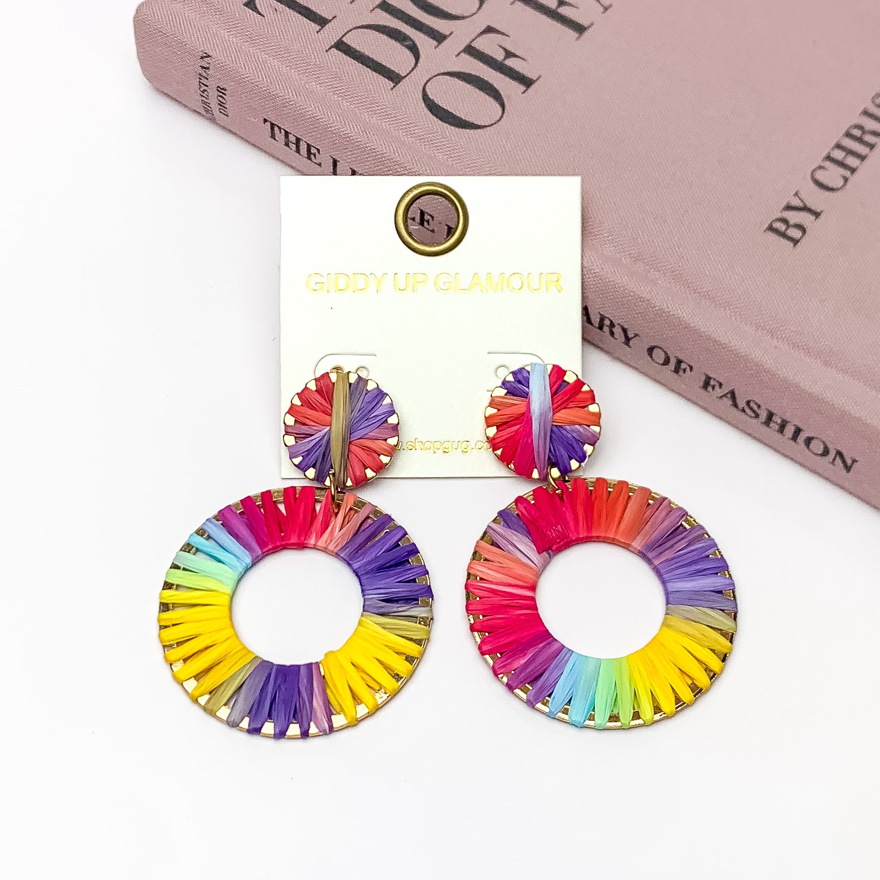 Rainbow Sunshine Open Circle Earrings in Multicolor. Pictured on a white background with a book in the top right corner.