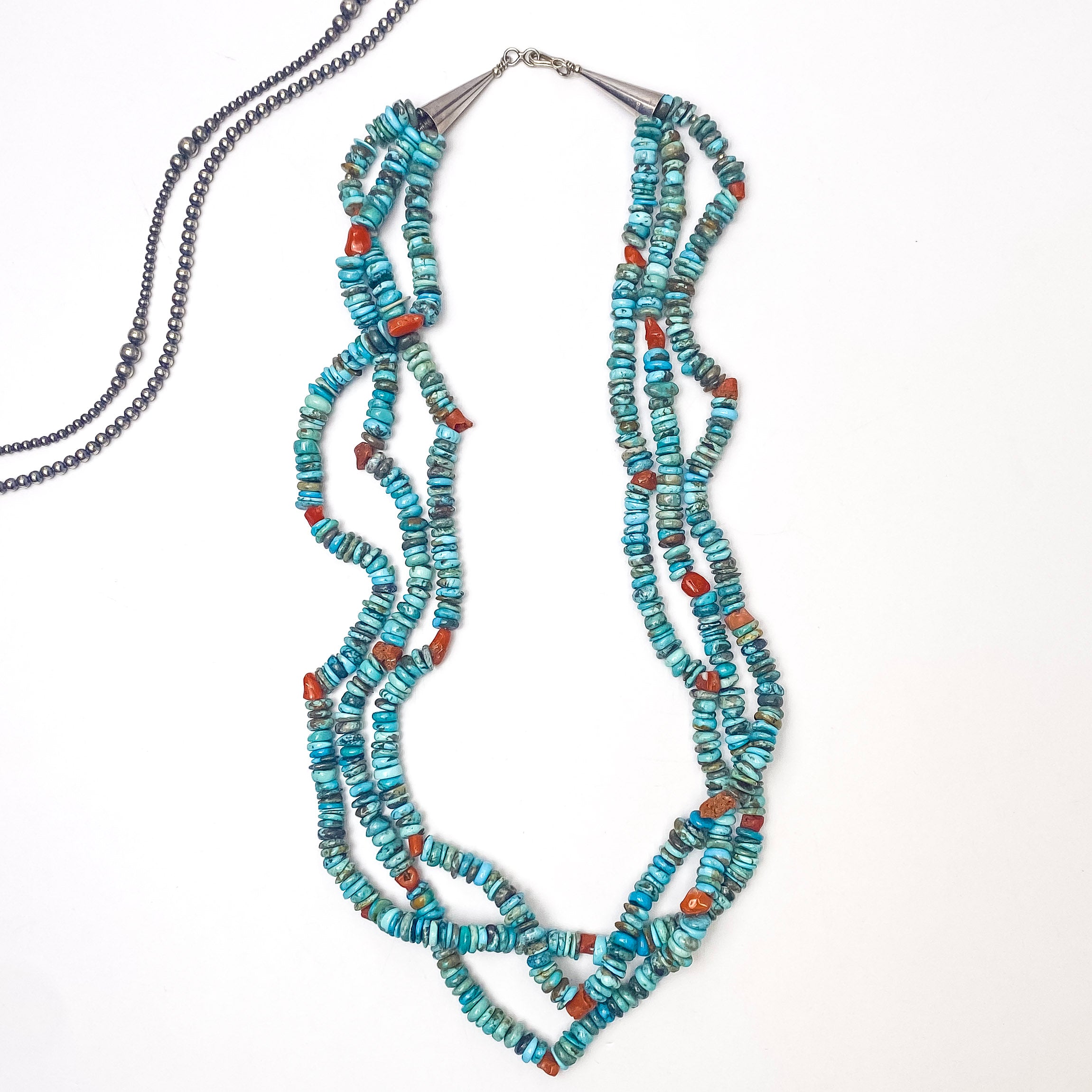 In the picture is a three strand necklace with natural turquoise and coral beading with a white background
