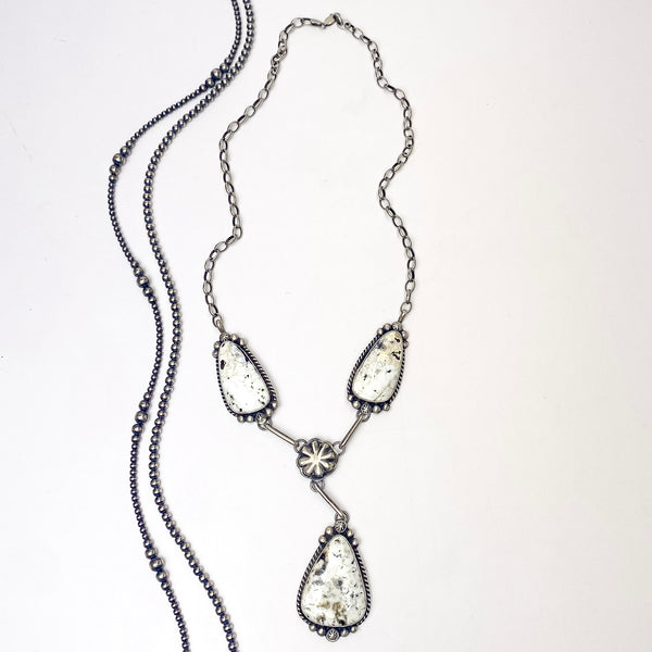 In the picture is a handmade augustine largo with sterling silver and white buffalo, this stunning necklace features  drop triangle pendants and a flower middle with a white background