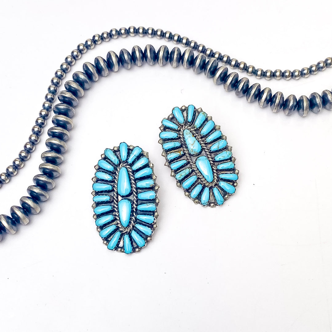 In the picture is a long oval shaped stud earring in a blue remix color with a white background