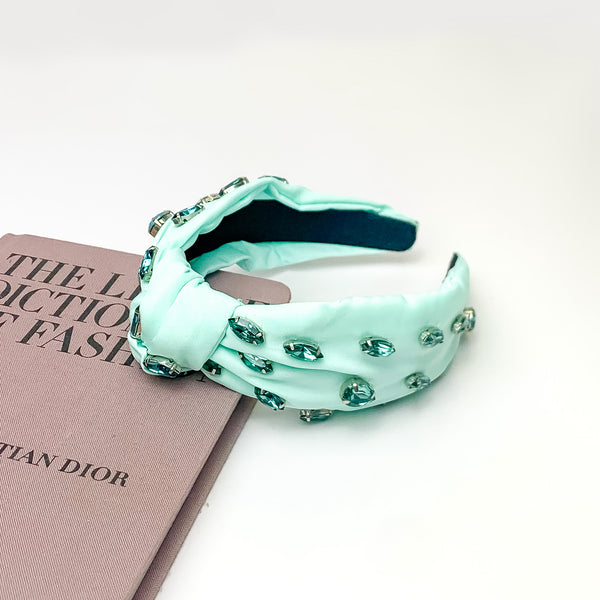Crystal Detailed Knot Headband in Mint Green. Pictured on a white background with the headband laying against a pink book. 
