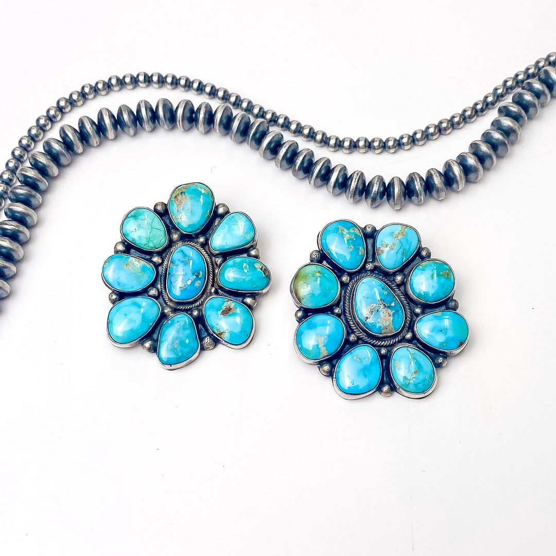 In the picture is a sterling silver flower stud cluster in Remix Blue with a white background