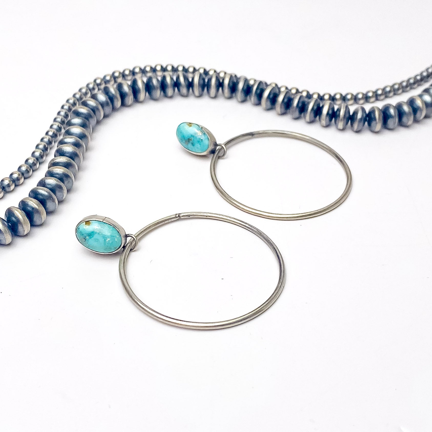 In the picture are handmade stud turquoise hoop earrings with a white background