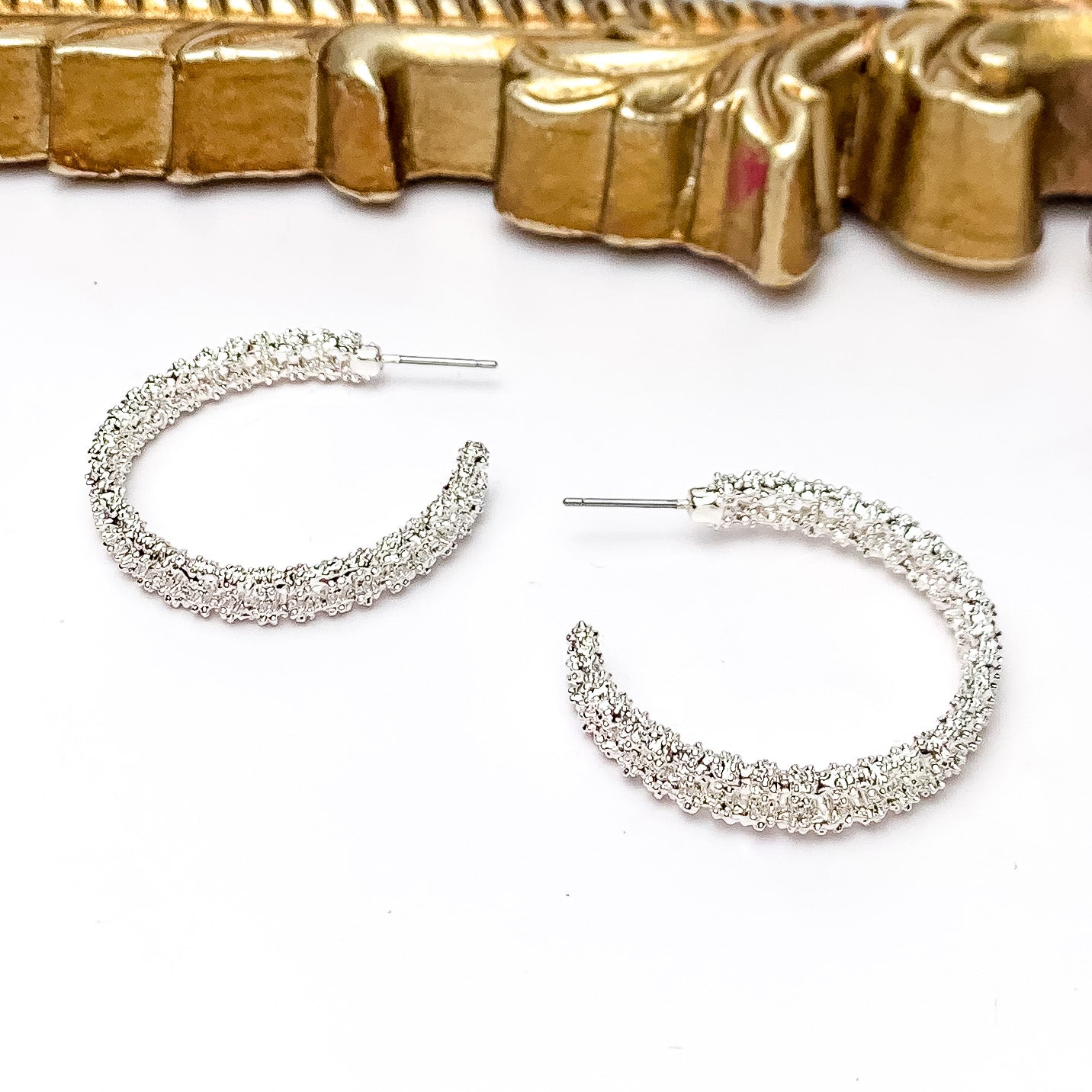 Worry Free Medium Silver Tone Textured Hoop Earrings. Pictured on a white background with a gold frame above the earrings. 