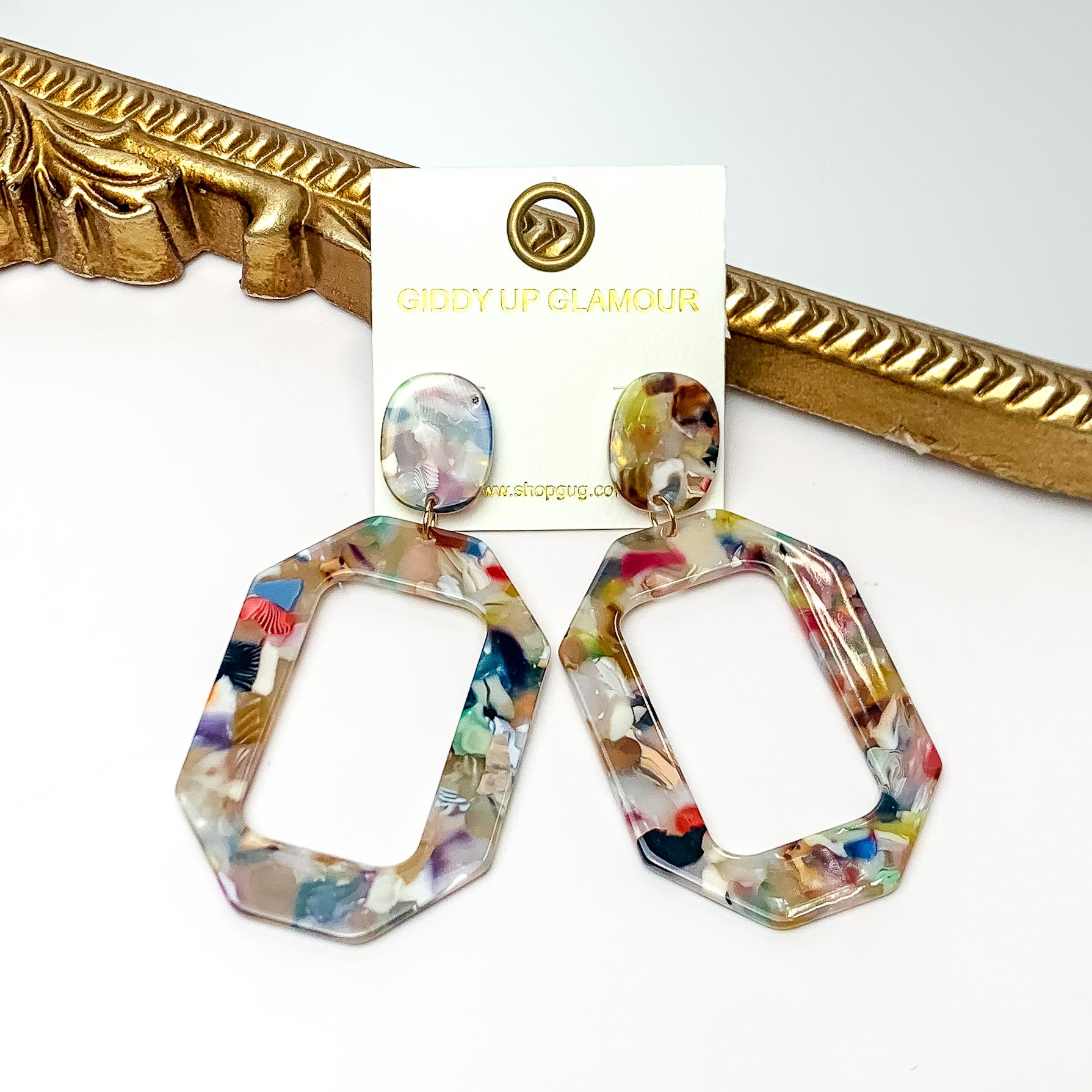 Malibu Marble Open Rectangle Earrings in multicolor. Pictured on a white background with the earrings laying on a gold frame.