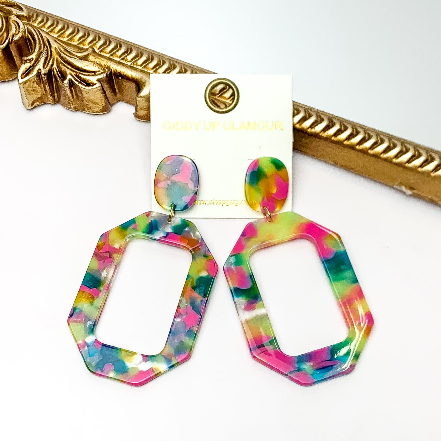 Malibu Marble Open Rectangle Earrings in Pink and Green Multicolor. Pictured on a white background with the earrings laying on a gold frame.