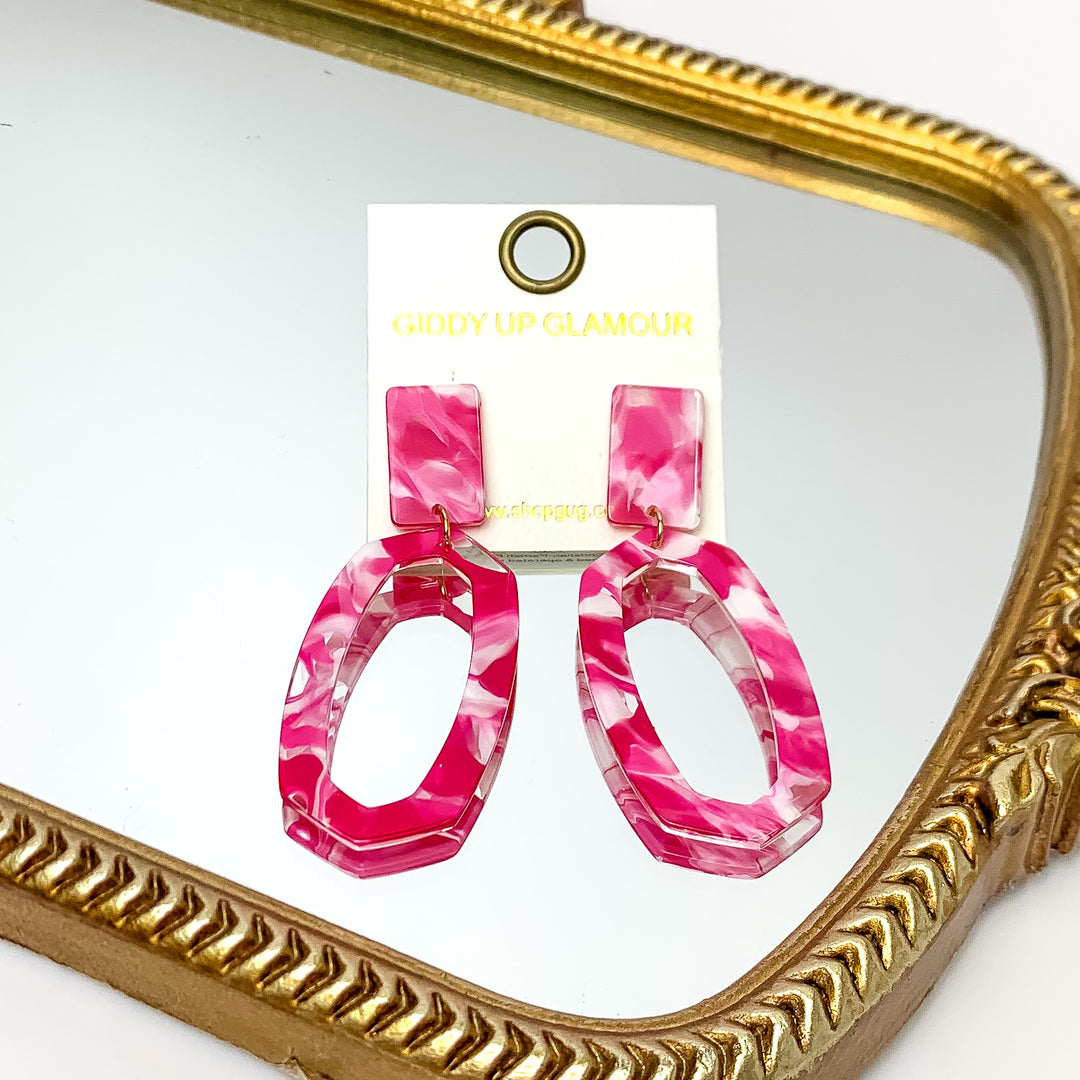 Miami Marble Open Oval Earrings in Hot Pink. Pictured on a white background with the earrings laying on a mirror.