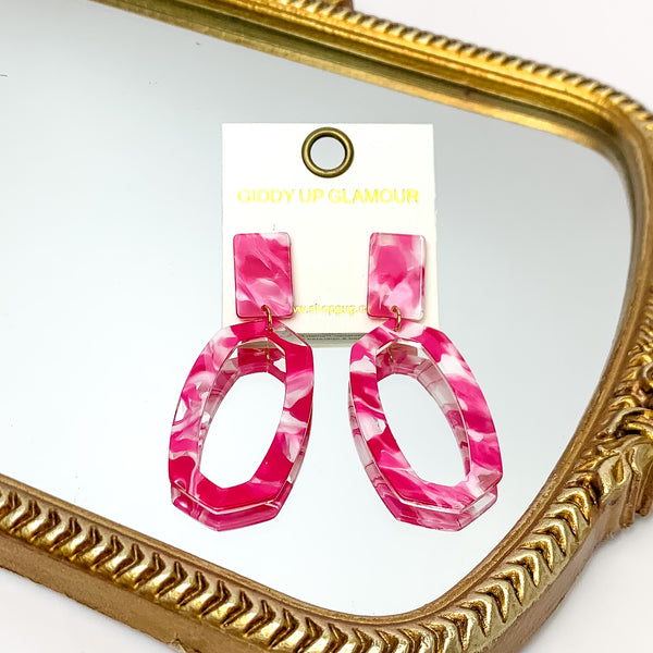 Miami Marble Open Oval Earrings in Hot Pink. Pictured on a white background with the earrings laying on a mirror.