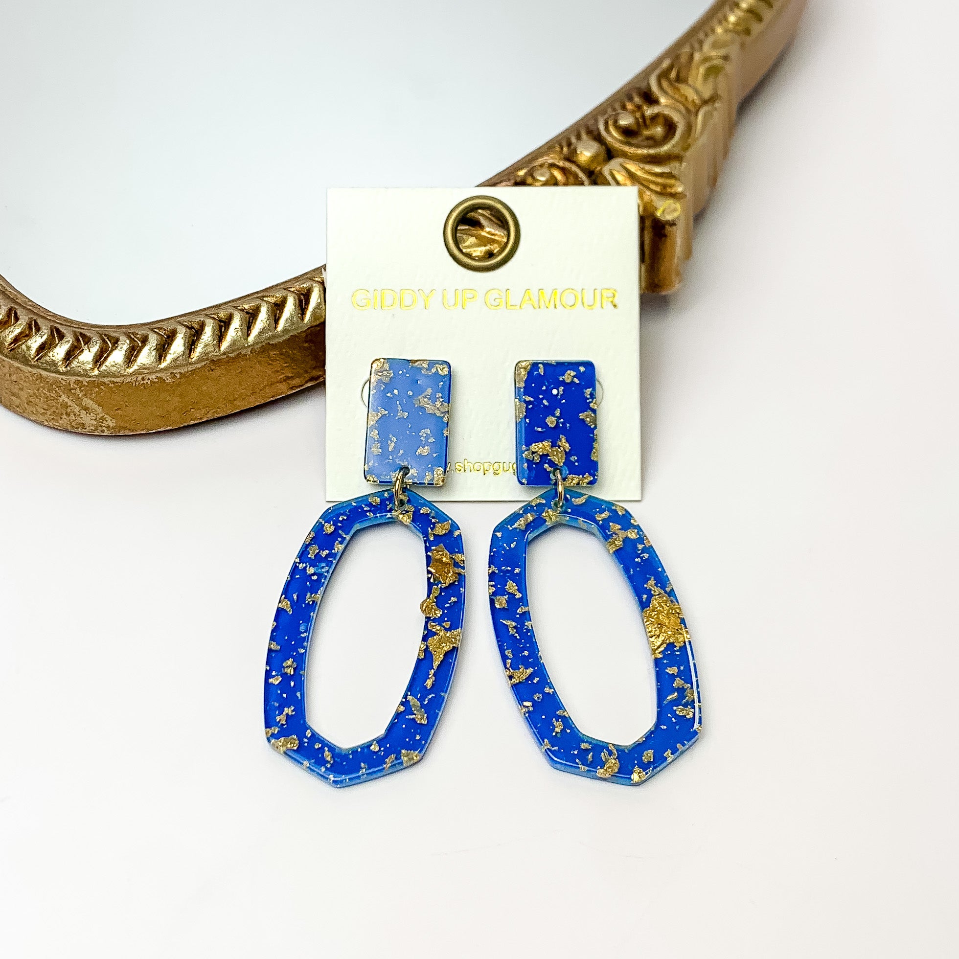 Miami Marble Open Oval Earrings in Royal Blue. Pictured on a white background with the earrings against a gold frame.