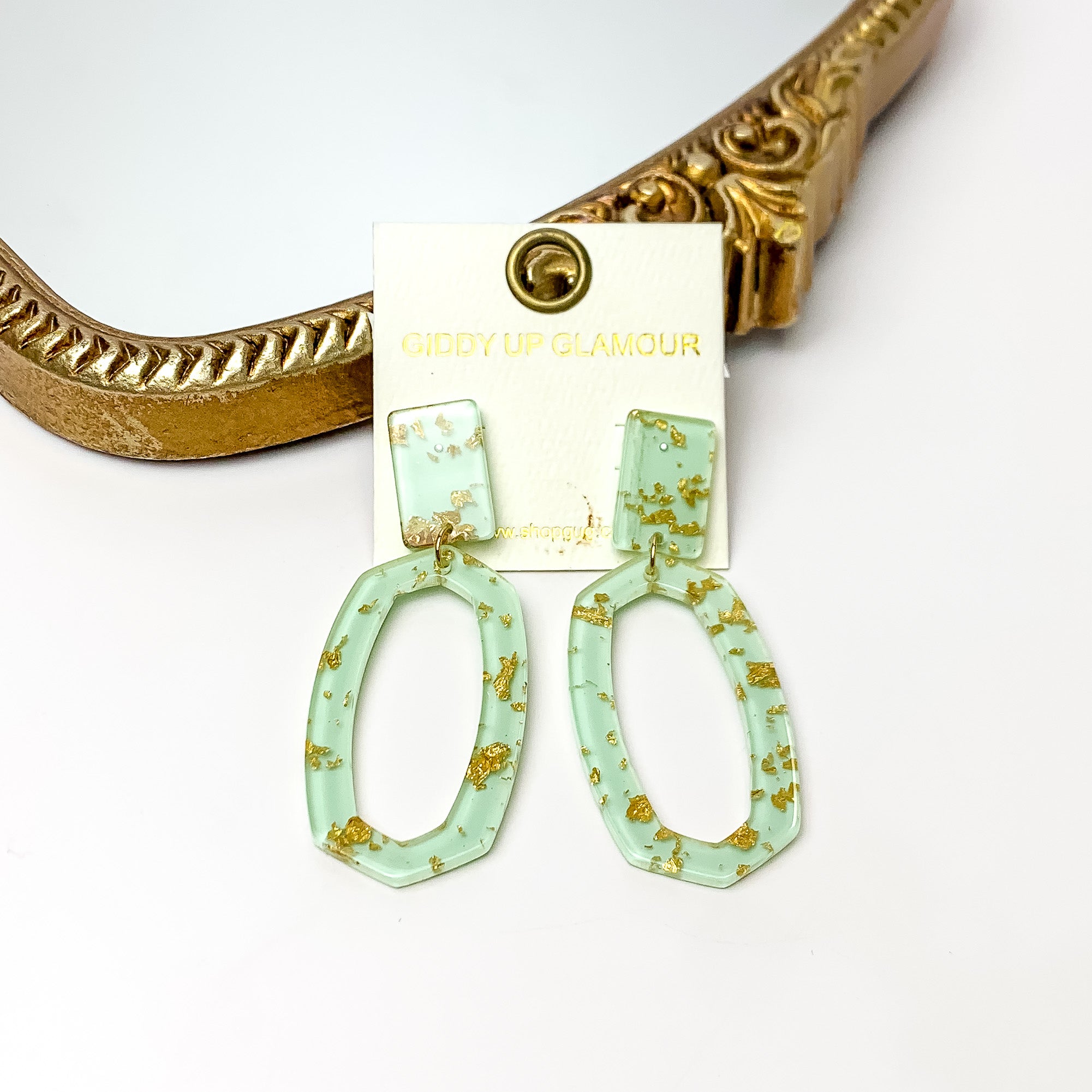 Miami Marble Open Oval Earrings in Light Green. Pictured on a white background with the earrings against a gold frame.