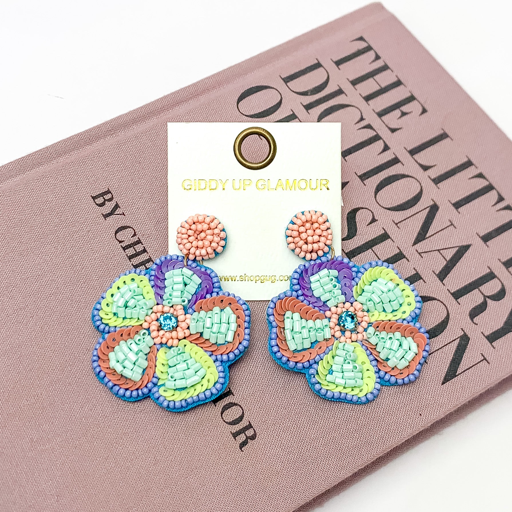 Beaded Flower Earrings in Pastel Multicolor. Pictured on a white background with the earrings laying on a book.