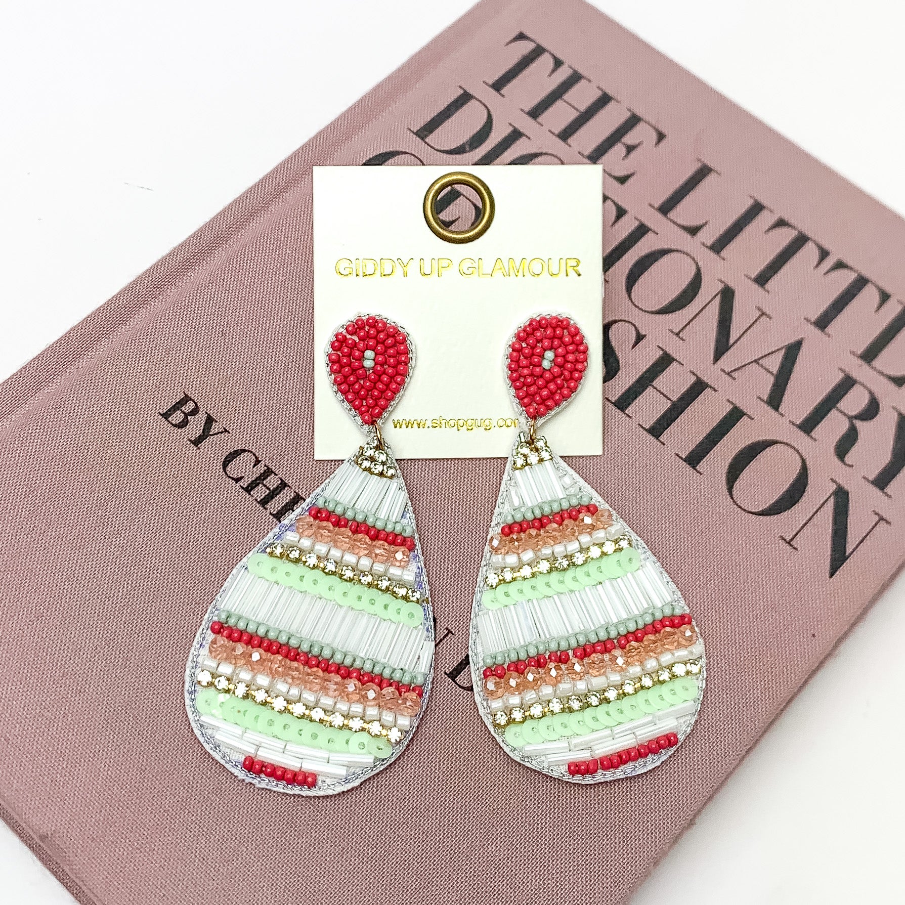 Beaded Teardrop Earrings in Multicolor With Clear Crystals. Pictured on a white background with the earrings laying on a book.