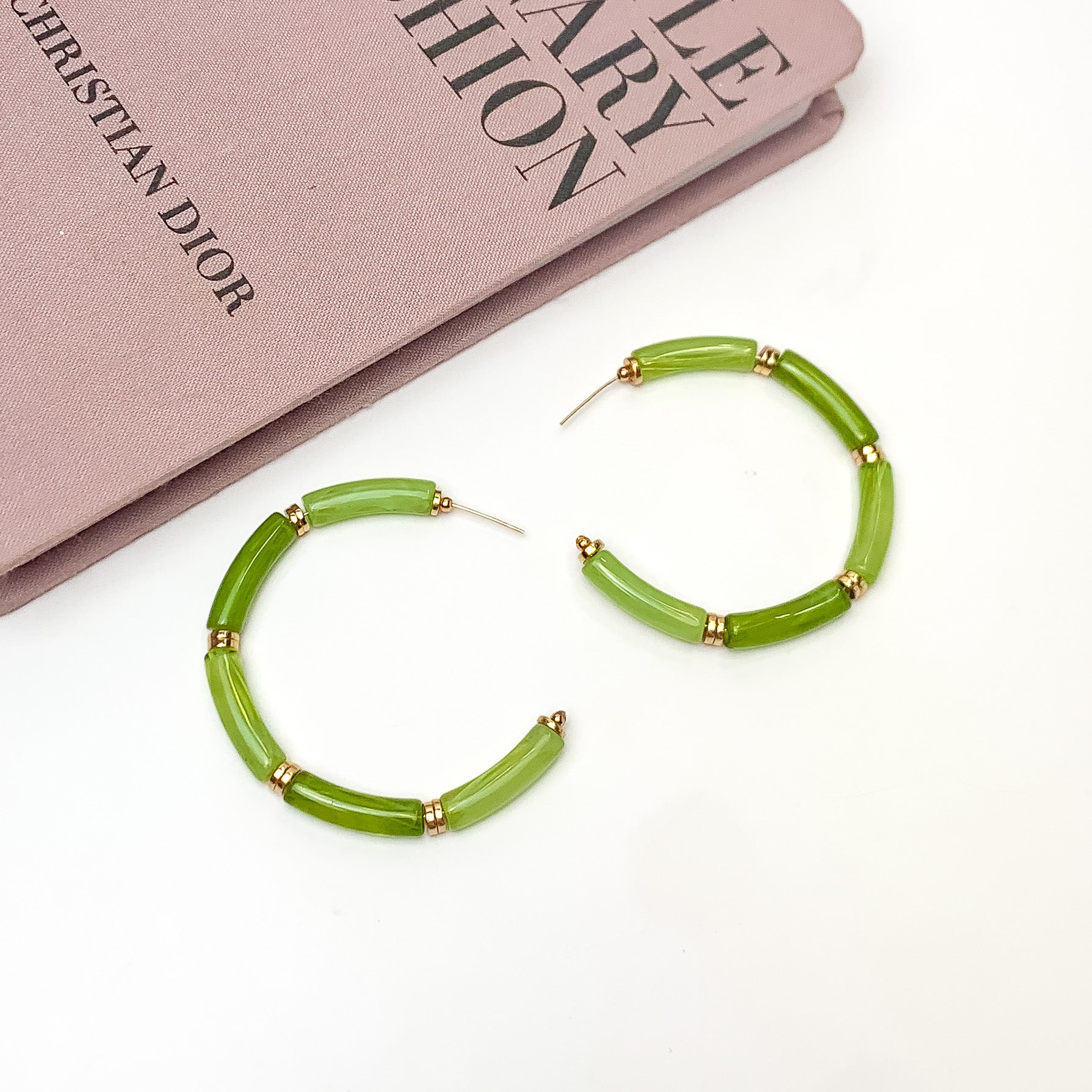 Island Style Tube Beaded Hoop Earrings Green. Pictured on a white background with a book in the top left corner.