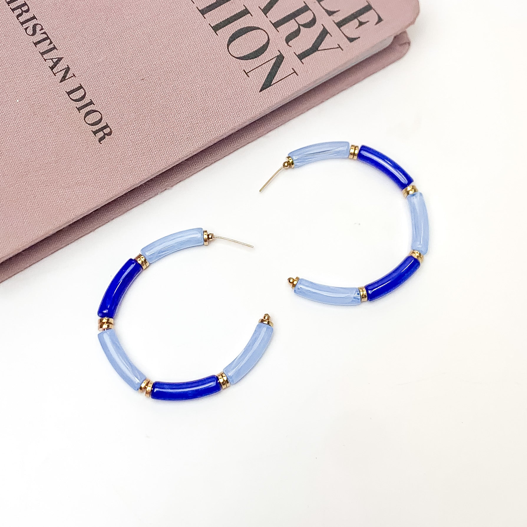 Island Style Tube Beaded Hoop Earrings Royal Blue. Pictured on a white background with a book in the top left corner.