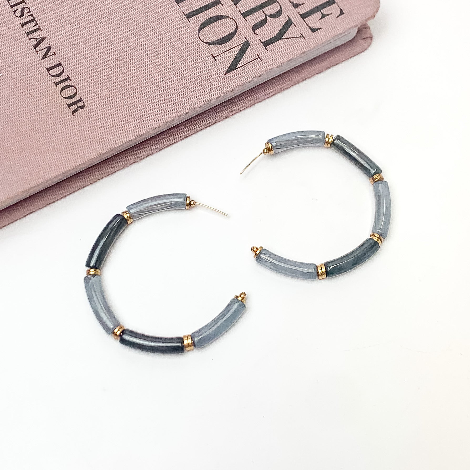 Island Style Tube Beaded Hoop Earrings Gray. Pictured on a white background with a book in the top left corner.