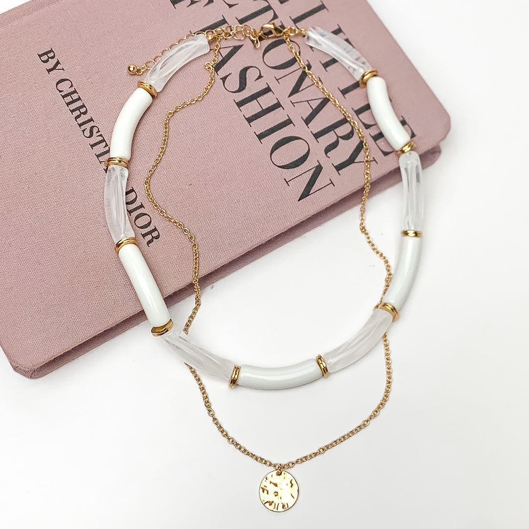 Perfect Paradise Tube Necklace With Second Gold Tone Chain Necklace. Pictured on a white background with the necklace laying on a book.