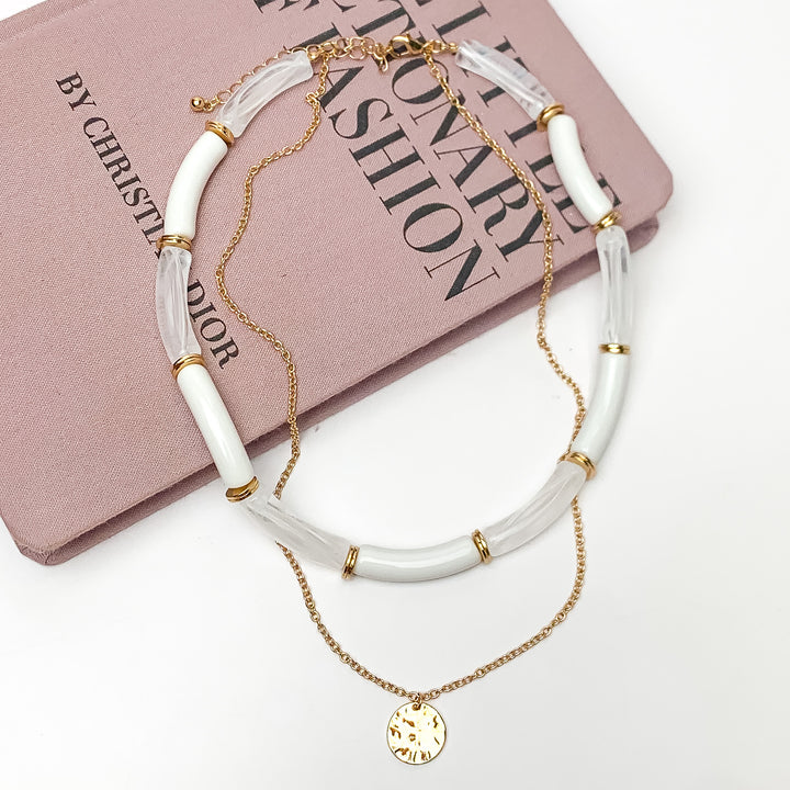 Perfect Paradise Tube Necklace With Second Gold Tone Chain Necklace. Pictured on a white background with the necklace laying on a book.
