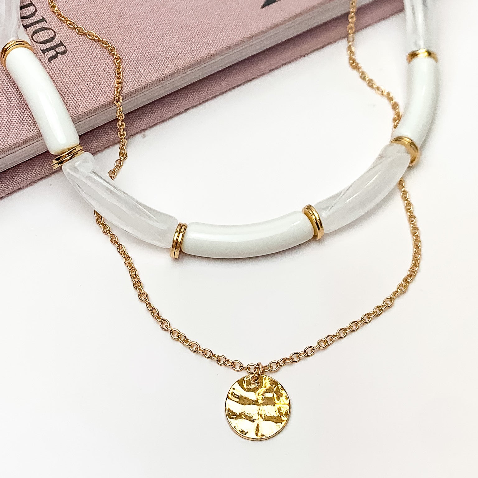 Perfect Paradise Tube Necklace With Second Gold Tone Chain Necklace. Pictured on a white background with the necklace laying on a book.