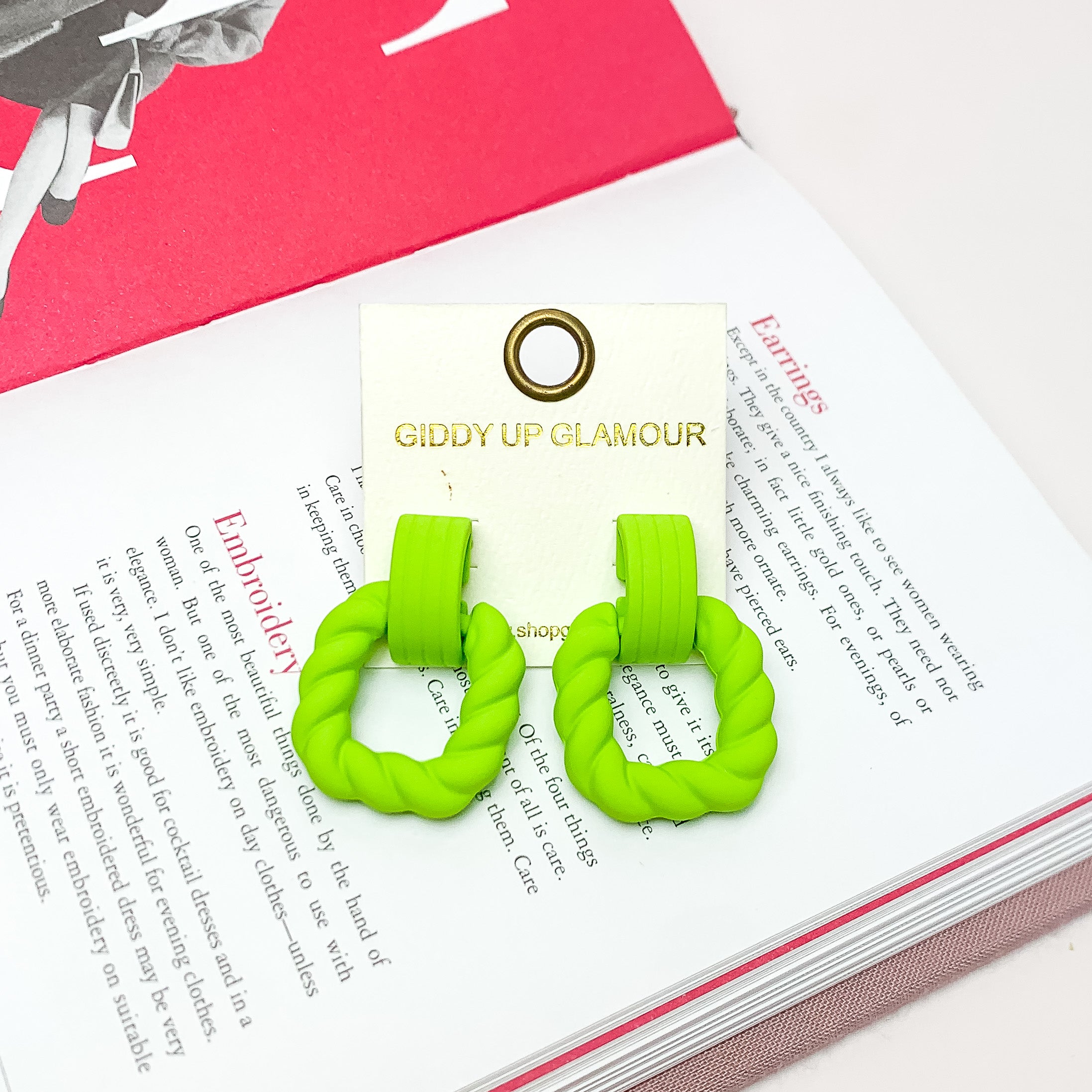 Ready to Party Twisted Square Earrings in Neon Green. Pictured on an open page of a book.