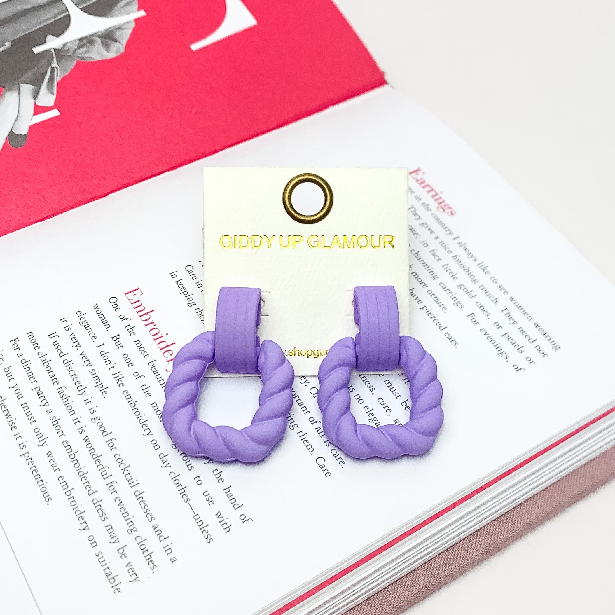 Ready to Party Twisted Square Earrings in Lavender. Pictured on an open page of a book.