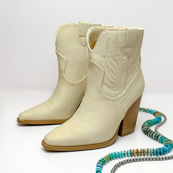 Not My First Rodeo Western Stitch Heeled Ankle Booties in Beige. Pictured on a white background with jewelry laying on the platform.