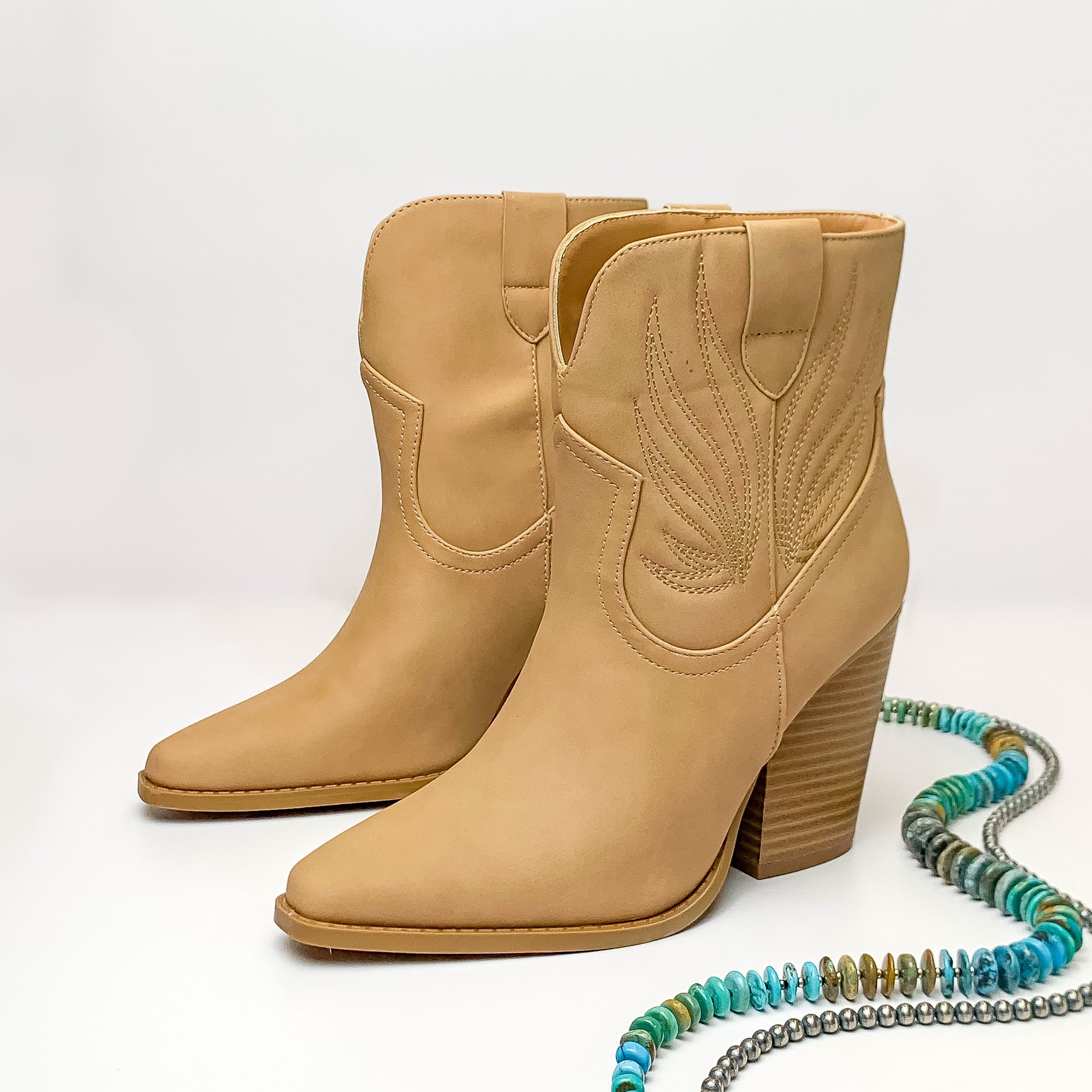 Not My First Rodeo Western Stitch Heeled Ankle Booties in Tan. Pictured on a white background with jewelry laying on the platform.