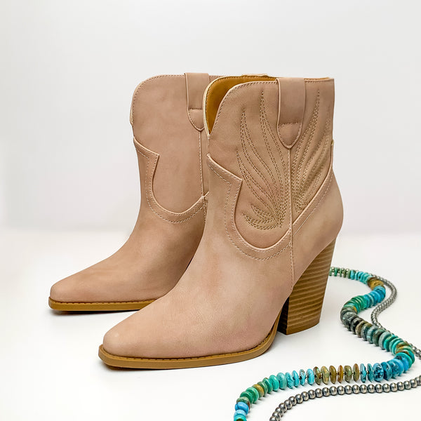 Not My First Rodeo Western Stitch Heeled Ankle Booties in Blush Nude. Pictured on a white background with jewelry pieces laying on the platform.