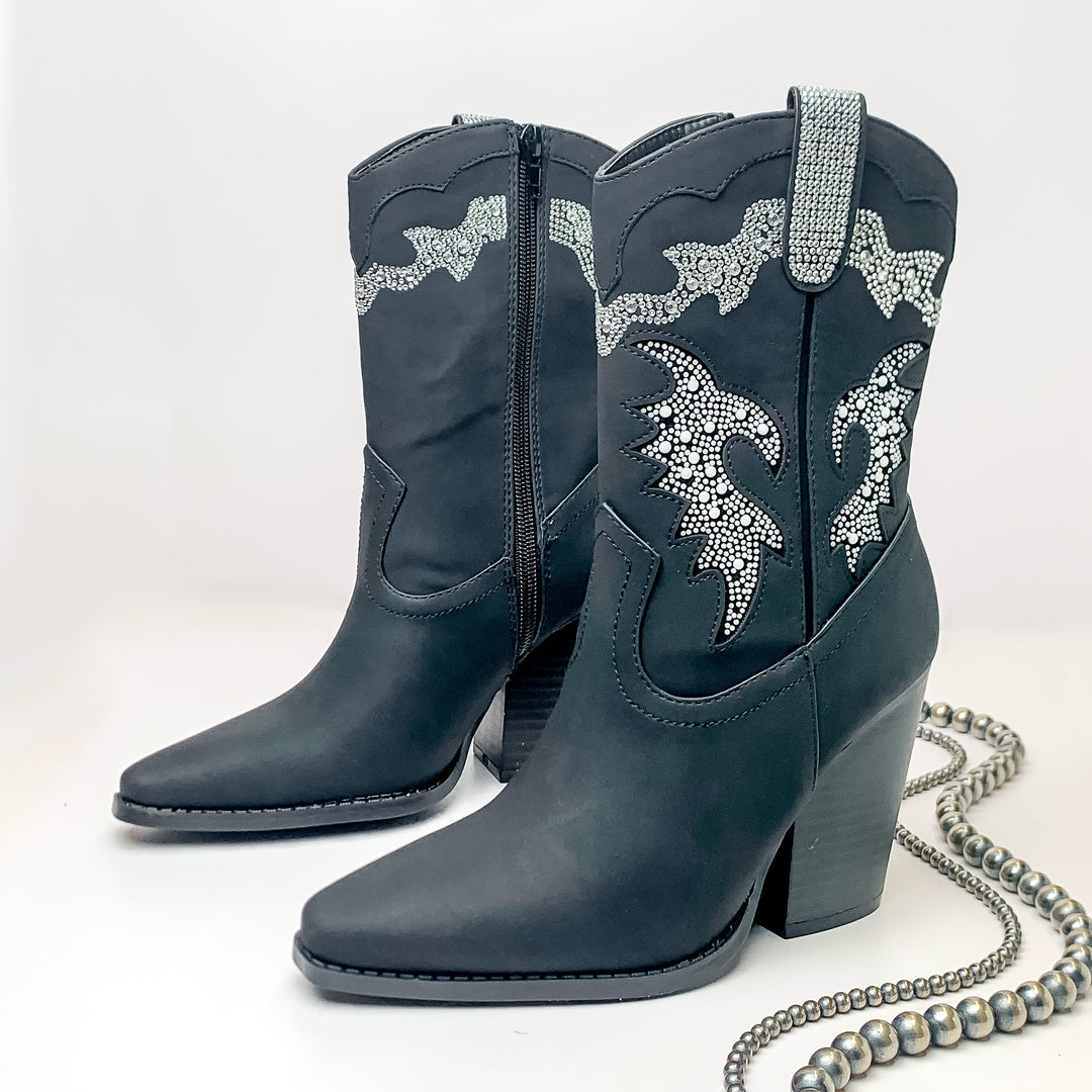 The Jolene Heeled Ankle Booties with Clear Crystals in Black. Pictured on a white background with jewelry laying on the platform. 