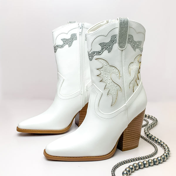 The Jolene Heeled Ankle Booties with Clear Crystals in White. Pictured on a white background with jewelry laying on the platform.