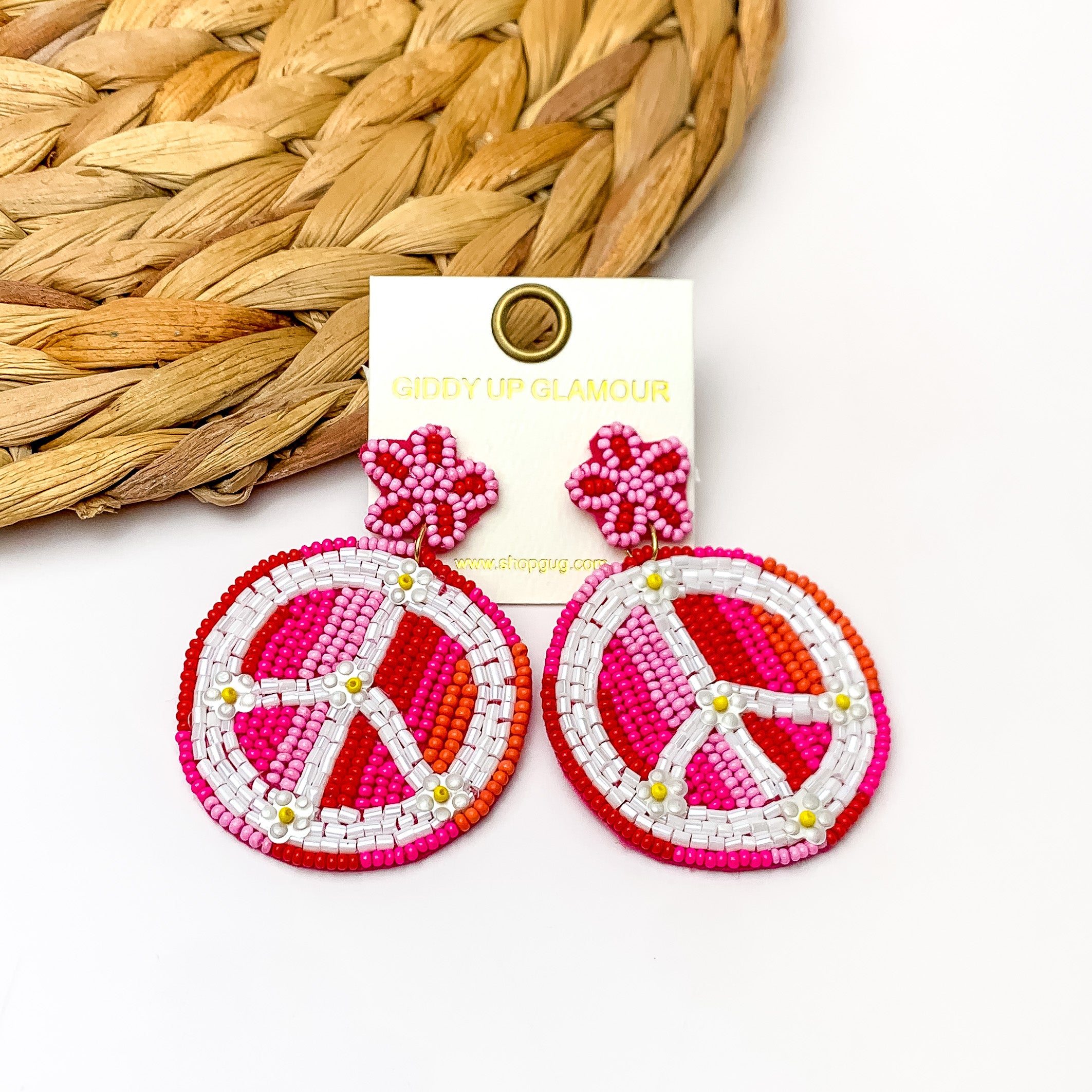 Beaded Peace sign Earrings With Star Post in Fuchsia. Pictured on a white background with a brown wood like decoration in the top left corner.